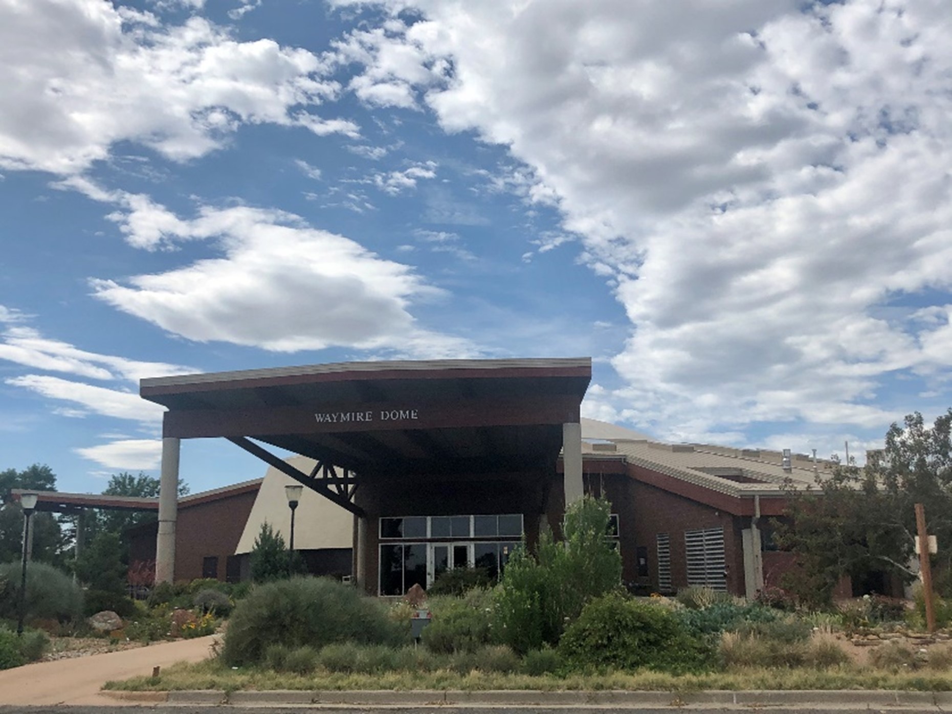 Waymire-Dome entrance under a partly cloudy sky with surrounding greenery