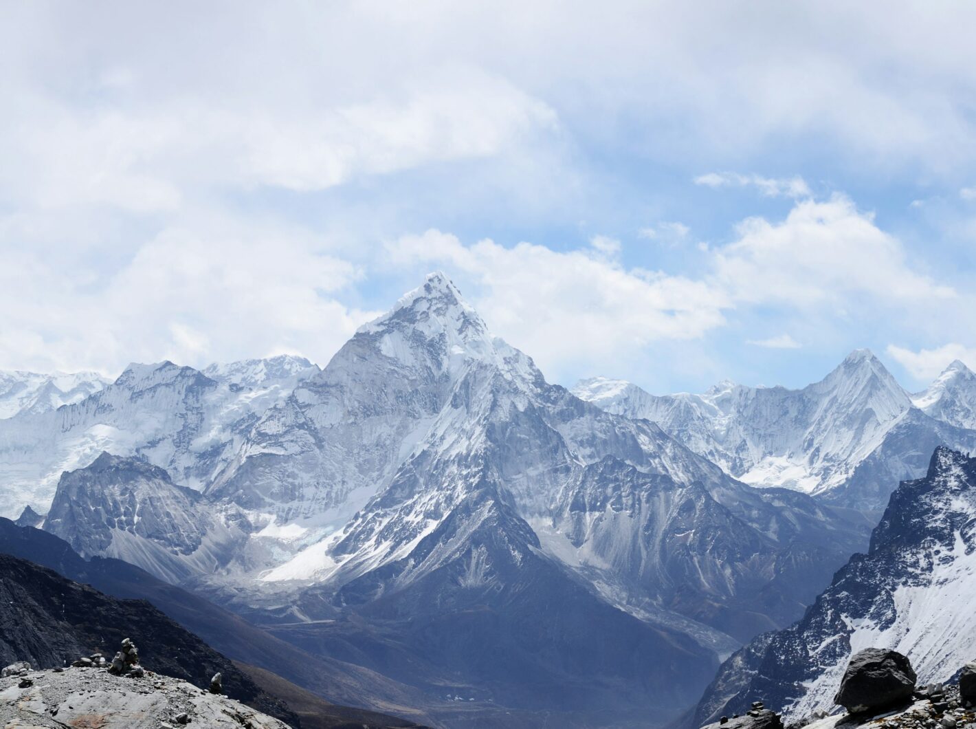 Snow-covered mountain range under a blue sky with clouds